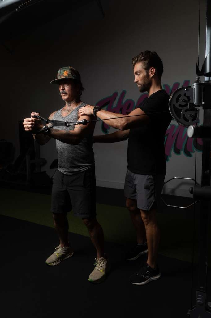 Adrien Maggione coaching a client on the cable machine at Maggione Fit